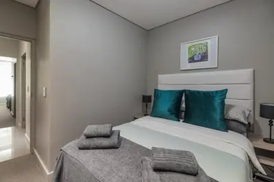 a bedroom with a large bed with blue pillows at Modern Family Flat Andringa Walk in Stellenbosch