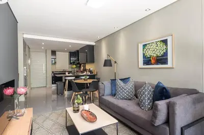 a living room with a couch and a kitchen at Modern Family Flat Andringa Walk in Stellenbosch