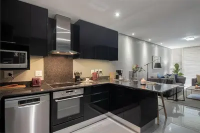a kitchen with black cabinets and stainless steel appliances at Modern Family Flat Andringa Walk in Stellenbosch
