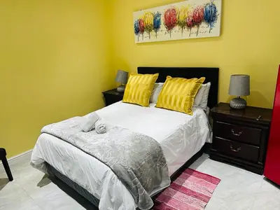 a bedroom with a bed with yellow walls at BOSTON HOUSE in Cape Town