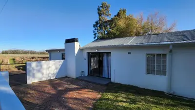 a white house with a door on a yard at Sandrivier Farm Stay in Worcester
