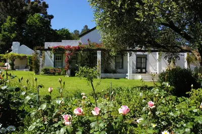 a white house with flowers in front of it at L'Auberge Chanteclair in Franschhoek