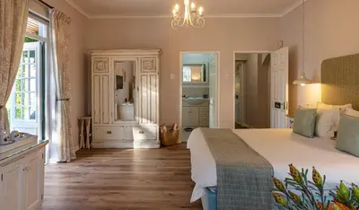 a bedroom with a large bed and a bathroom at L'Auberge Chanteclair in Franschhoek