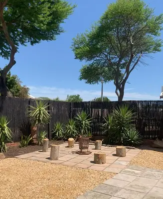 a patio with a bench and trees in front of a fence at Apartment with garden in Cape Town