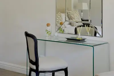 a glass desk with a chair and a mirror at Fransvliet Guest House in Franschhoek