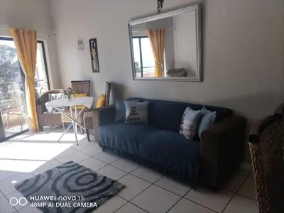 a living room with a blue couch and a mirror at Nautica Strand in Cape Town