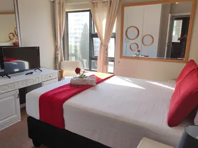 a bedroom with a large bed and a television at Nautica Strand in Cape Town