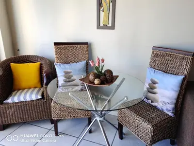 a room with a glass table and two chairs at Nautica Strand in Cape Town