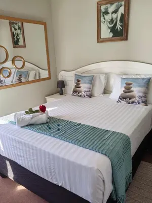 a bedroom with a large white bed with a mirror at Nautica Strand in Cape Town