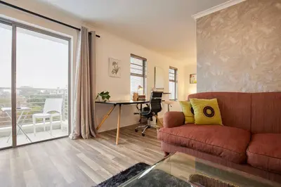 a living room with a couch and a desk and a window at Rondebosch Central in Cape Town