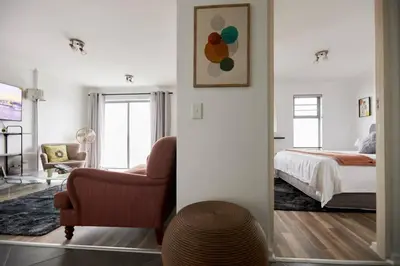 a bedroom with a bed and a chair and a mirror at Rondebosch Central in Cape Town