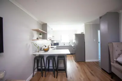 a kitchen with a sink and a counter with stools at @Villa de Vie holiday apartment in Cape Town