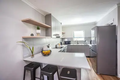 a kitchen with a large white counter and stools at @Villa de Vie holiday apartment in Cape Town