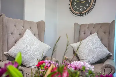 two chairs with pillows and a clock on the wall at @Villa de Vie holiday apartment in Cape Town