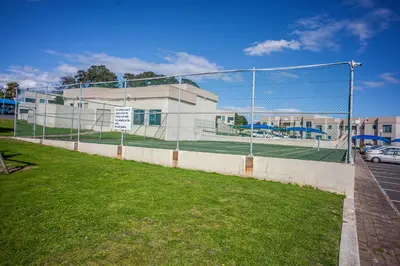 a chain link fence with a tennis court behind it at @Villa de Vie holiday apartment in Cape Town