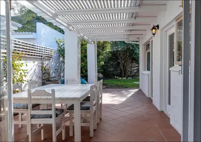 a white pergola on a patio with a table and chairs at SeaCrest Cottage in Hermanus