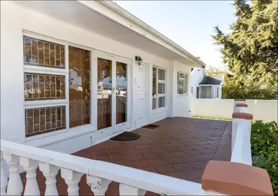 a white house with a white fence and a porch at SeaCrest Cottage in Hermanus