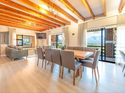 a dining room with a wooden table and chairs at Aan de Paarlberg in Paarl