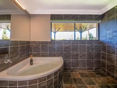 a bathroom with a tub and a window at Aan de Paarlberg in Paarl