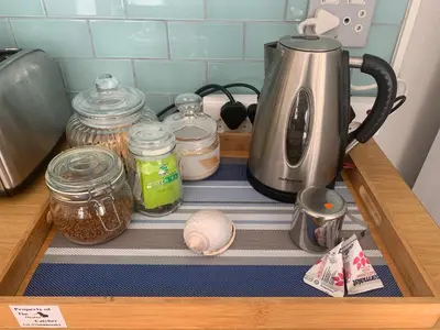 a kitchen counter with a coffee maker and jars of food at OysterCatcher Self-Catering Accommodation Strand in Cape Town