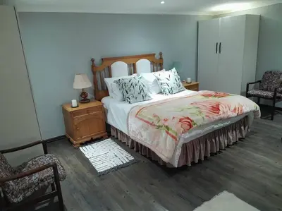 a bedroom with a bed and a table and a chair at Magnolia Cottage in Cape Town