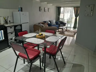 a kitchen and living room with a table and chairs at Magnolia Cottage in Cape Town