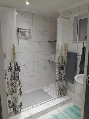 a white bathroom with a shower and a sink at Magnolia Cottage in Cape Town