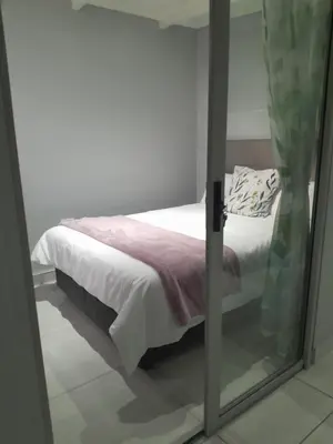 a bed is seen through a glass door at Magnolia Cottage in Cape Town