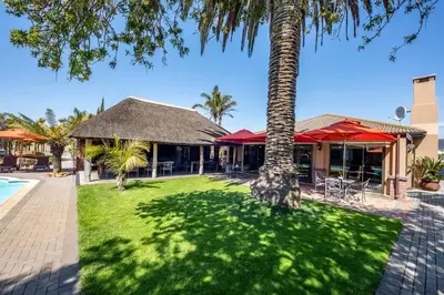 a resort with a palm tree and a pool at Excellent Guest House in Bellville