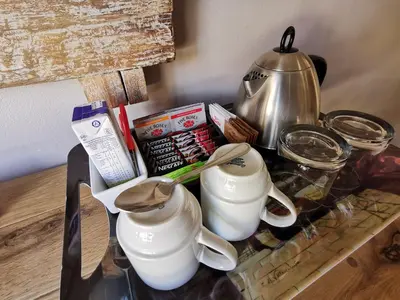 a table with two spoons and a tea kettle at Excellent Guest House in Bellville