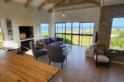 a living room with a couch and chairs and windows at Jock's Bay View in Bettyʼs Bay