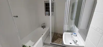 a bathroom with a tub and a sink and a shower at Jock's Bay View in Bettyʼs Bay