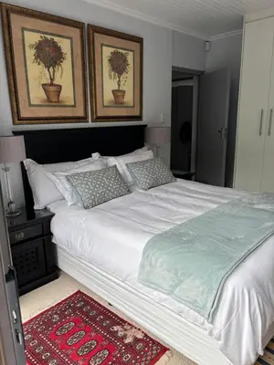 a bedroom with a large white bed with two pictures at Self Catering Luke Drive Onrus in Hermanus