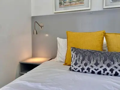 a bed with yellow and white pillows and a lamp at #Restyourcase in Stellenbosch