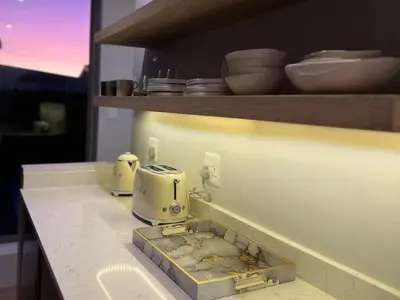 a kitchen counter with a sink and dishes on a shelf at Quaint Cottage in Hermanus