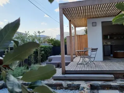 a patio with a table and chairs on a deck at Quaint Cottage in Hermanus