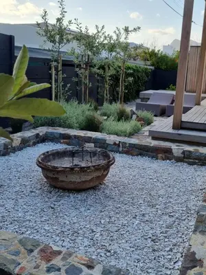 a garden with a stone fire pit in the middle at Quaint Cottage in Hermanus