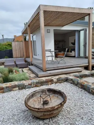 a backyard with a wooden deck with a fire pit at Quaint Cottage in Hermanus