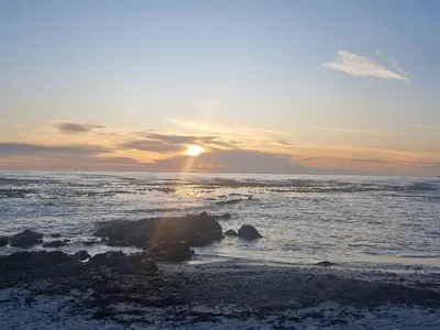 a sunset over the ocean with the sun setting at Quaint Cottage in Hermanus