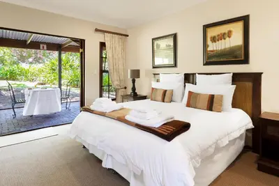 a bedroom with a large white bed with towels on it at Ongegund Lodge in Somerset West