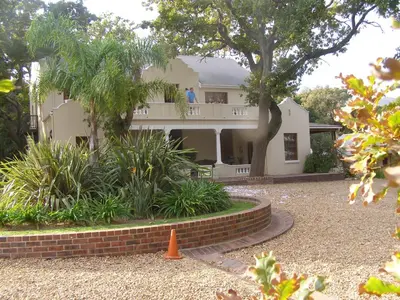 a white house with a tree and a brick yard at Ongegund Lodge in Somerset West