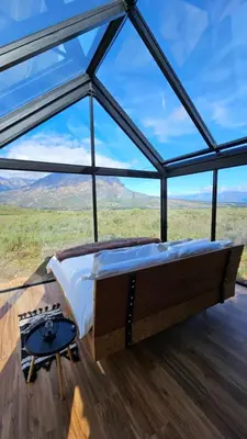 a bed in a room with a large glass window at Little Acre Luxury Pods in Tulbagh