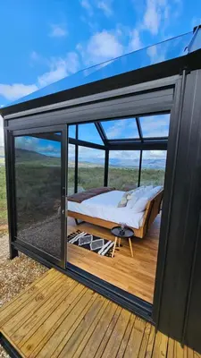 a bed on a deck with a large window at Little Acre Luxury Pods in Tulbagh