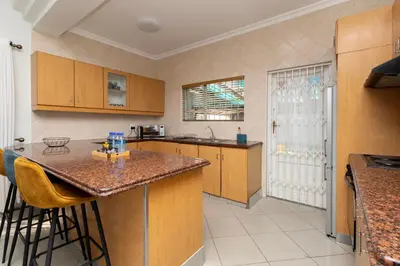 a kitchen with wooden cabinets and a island with bar stools at SERENA INN Apartment no5 in Cape Town