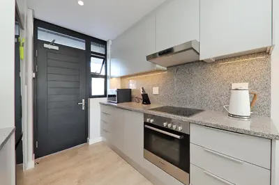 a kitchen with white cabinets and a black door at 002 Burmeister on Park- 2 minute walk from the beach in Cape Town