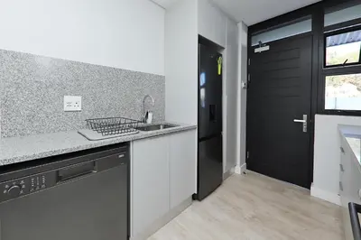 a kitchen with a sink and a black door at 002 Burmeister on Park- 2 minute walk from the beach in Cape Town
