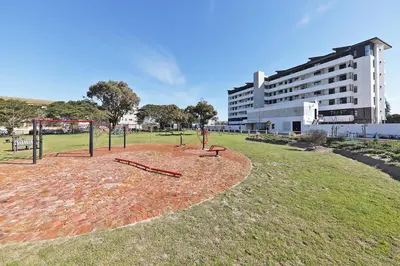 a park with a playground with trees and a building at 002 Burmeister on Park- 2 minute walk from the beach in Cape Town