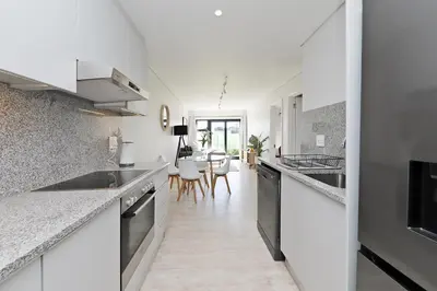 a kitchen with white counter tops and a dining room at 002 Burmeister on Park- 2 minute walk from the beach in Cape Town
