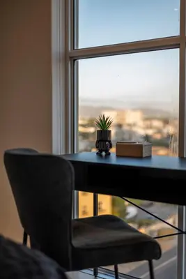 a table with a plant on it next to a window at Stylish Sunlit Ocean View Oasis! in Cape Town