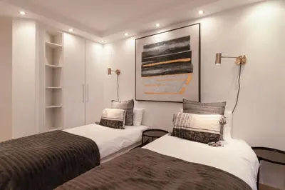 two beds in a room with a picture on the wall at Stylish Sunlit Ocean View Oasis! in Cape Town